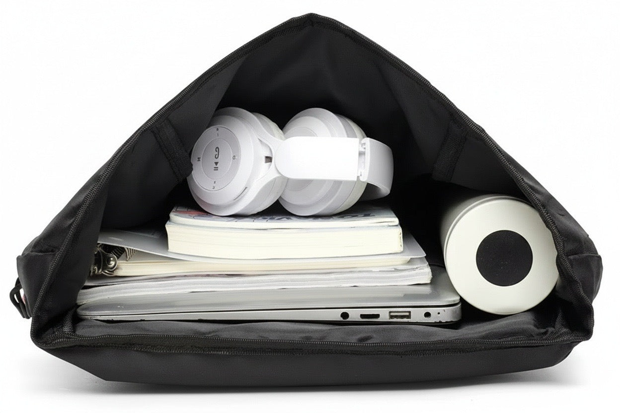 Geöffneter Rollverschluss-Rucksack von oben mit Blick ins Hauptfach, gefüllt mit Laptop, Notizbüchern, Bluetooth-Kopfhörern und einem tragbaren Lautsprecher – ideal für den urbanen Alltag