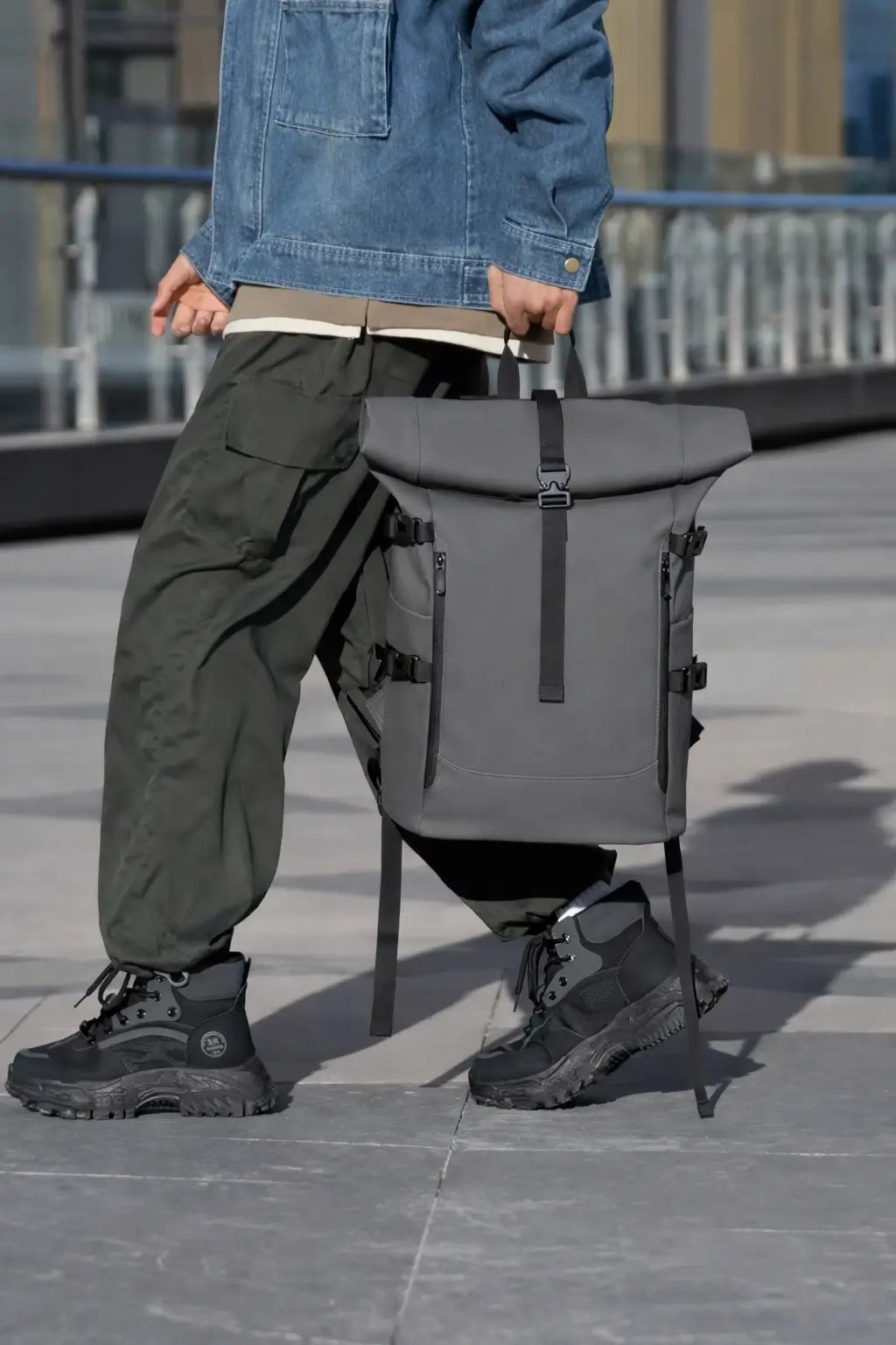 Rolltop Rucksack in Grau getragen über der Schulter in urbaner Umgebung